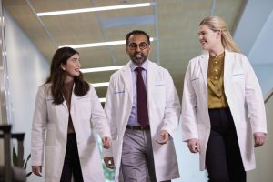 Three Permanente physicians in discussion as they walk down corridor in a medical facility.