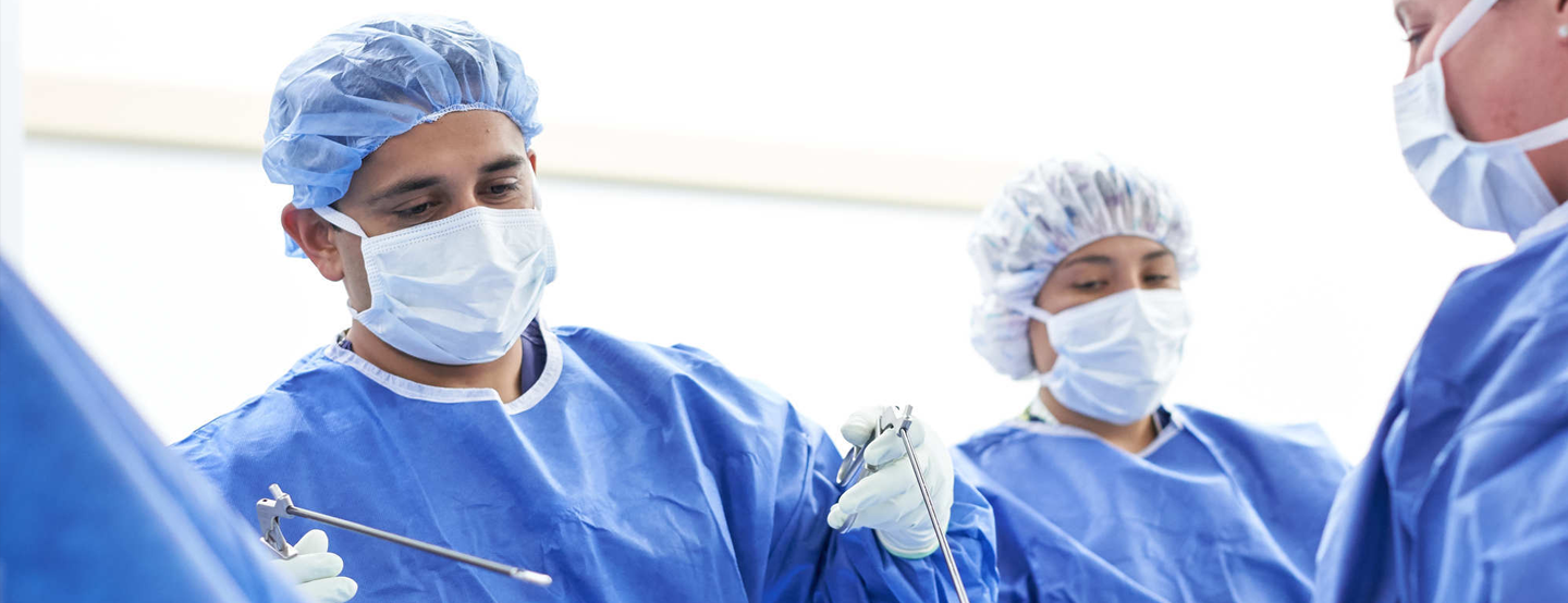 A Permanente physician, supported by clinical staff, performs surgery on an unseen patient. Collaboration is key to our care model.