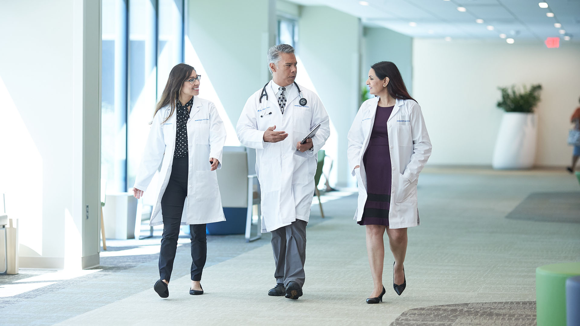 Three doctors talking and walking in hallway together